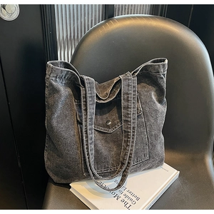 Detail of vintage washed denim tote bag with functional cargo pocket and metal snap button