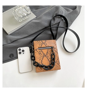 Detail of a mini orange snake pattern crossbody bag with a thick black plastic chain