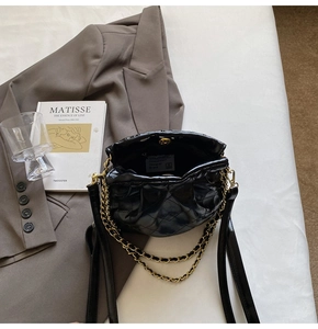 Detailed macro view of black quilted leather bucket bag with gold chain strap design