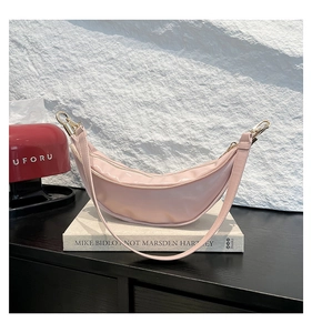 Detail of light pink patent leather croissant bag with gold metal zipper and slim strap