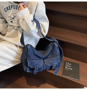 Detail of blue denim motorcycle bag showing metal buckle pockets and stitching textures