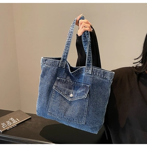 Detail of the front flap pocket with button on the vintage blue denim tote shoulder bag