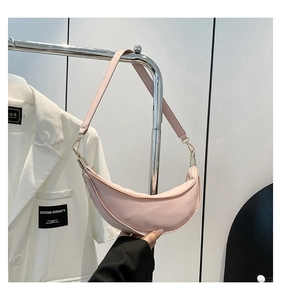 Detail of light pink crescent nylon bag showing polished gold hardware and fabric texture
