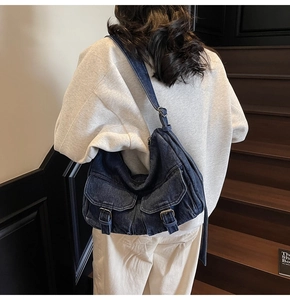 Detail view of a vintage dark blue denim shoulder bag with multi-pocket utility design