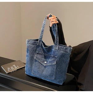 Detail of blue denim tote bag with front flap pocket and reinforced dual handles
