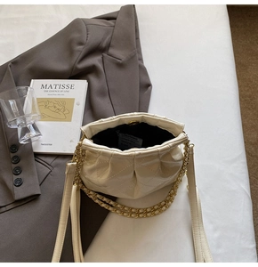 Detail of beige quilted cloud bag showing gold chain strap and magnetic snap closure