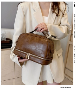 Detail view of the brown leather makeup bag with double zippers and handle for travel