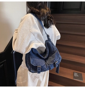 Detail of blue denim hobo bag showing front pockets with silver buckles and texture