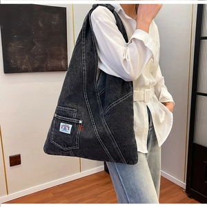 Detail of black washed denim hobo bag with contrast stitching and branded side pocket