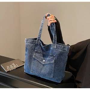 Close-up of deep blue denim tote bag featuring a practical metal button front pocket
