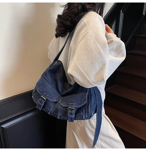 Detailed close-up of dark blue denim motorcycle bag showing metal buckle pockets and texture
