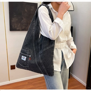 Detailed view of dark denim tote bag with functional side pocket and decorative patch