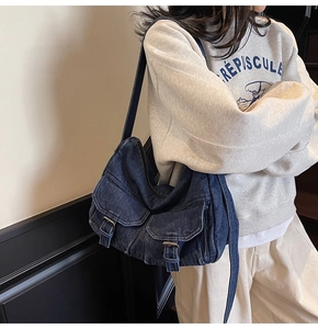 Detail of vintage blue denim shoulder bag with double flap pockets and wash effect