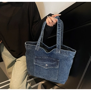 Detail of vintage blue denim tote bag with functional metal snap front pocket