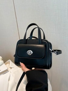 Minimalist black leather handbag with silver metallic lock and adjustable shoulder strap