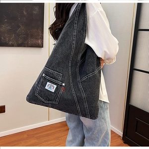 Detail of washed denim bag featuring contrast white stitching and embroidered pocket label
