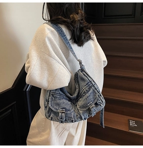 Detail of vintage blue denim shoulder bag featuring metal buckles and flap pockets