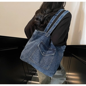 Model wearing large vintage blue denim tote bag with functional front flap pocket