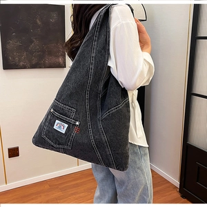 Detail of black washed denim crossbody bag featuring contrast stitching and rainbow patch