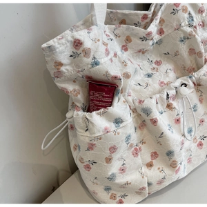Detail of the white lace floral tote bag featuring a practical side drawstring pocket