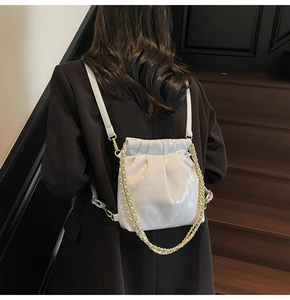 Detail view of cream quilted drawstring bucket bag with gold chain and leather straps