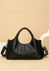 Close-up of black leather handbag with litchi texture and woven top handle detail