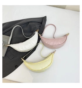 Detailed view of minimalist crescent bags in white, pink, and yellow faux leather textures