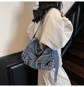 Detailed view of retro washed blue denim shoulder bag with silver buckle and cargo pockets