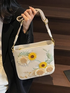 White crossbody bag with sunflower embroidery and a patterned woven shoulder strap