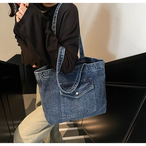 Detail of vintage denim tote bag showing front pocket with metal buckle and texture