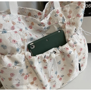 Close-up of floral lace tote bag featuring a functional drawstring side pocket for a tablet