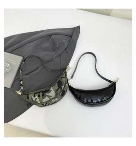 Flat lay of camo fabric and black glossy crescent bags with metallic zipper details