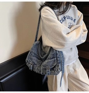 Detail of vintage denim motorcycle bag with multi-pocket design and washed blue finish