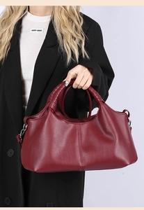 Detail of burgundy pebbled leather handbag with wrapped handles and silver metal buckles