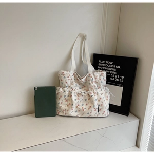 Close-up of floral canvas tote bag showing the front drawstring pocket and side compartment