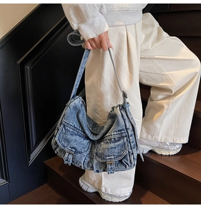 Detail of vintage blue denim hobo bag with metal buckle pockets and wide strap