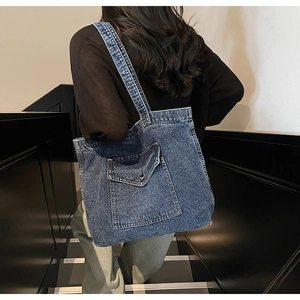 Detail view of large dark blue denim tote bag with front pocket shown on model