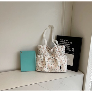 Detail of floral tote bag showing front drawstring pocket and canvas fabric texture