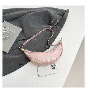 Detail showing pink half-moon dumpling bag size compared to a smartphone on a desk