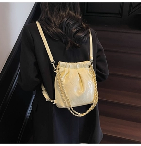 Detailed view of beige quilted faux leather backpack with chain strap on shoulder