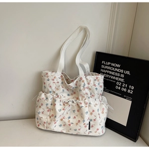 Detail showing the floral canvas texture and drawstring pocket on the beige tote bag
