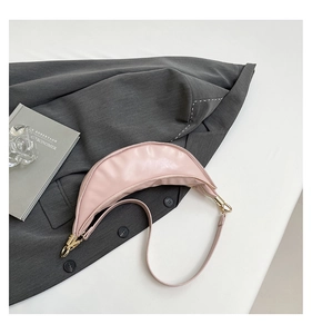 Detail of a light pink crescent bag showing soft glossy leather texture and gold hardware