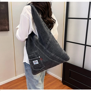 Detail of charcoal grey denim tote with white stitching and decorative logo patch
