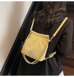 Detail of yellow quilted leather backpack with gold chain straps on a black blazer