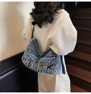 Detailed close-up of retro washed denim shoulder bag with buckle pockets on model