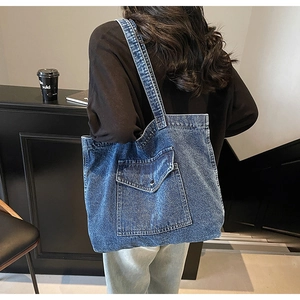 Detailed view of vintage blue denim tote bag with functional front flap pocket on model