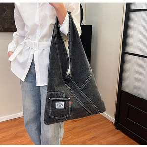 Detail of washed denim tote bag with functional pocket and INTO THE SPACE label
