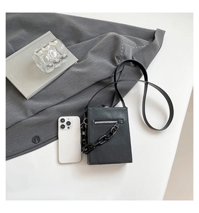 Detail view of black textured mini square bag with silver zipper and thick matte chain decor