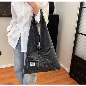 Macro shot of large black washed denim tote bag with white stitching and brand patch