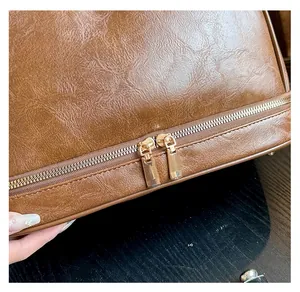 Macro detail of smooth golden double zippers on brown lychee pattern leather toiletry bag